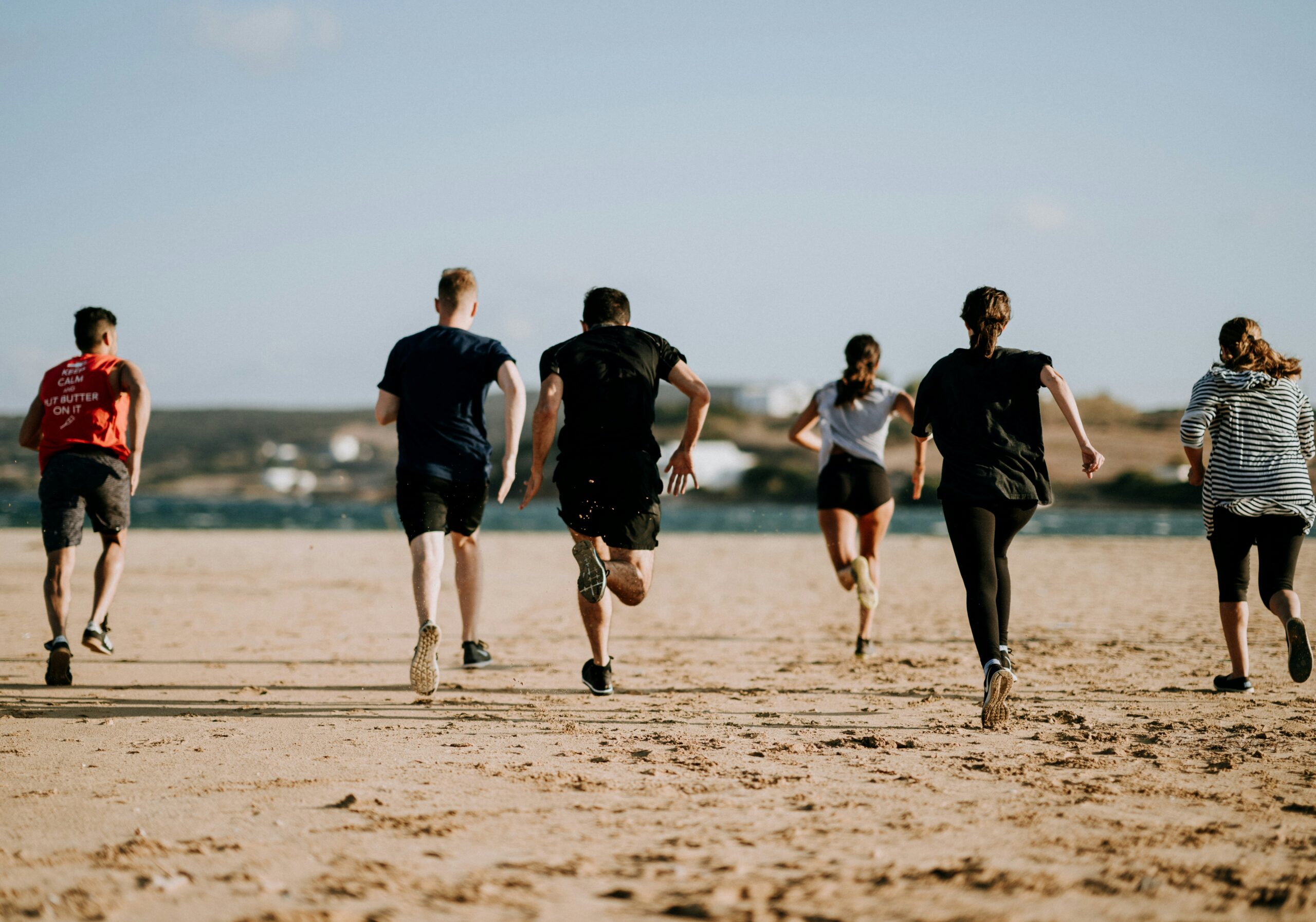Groep mensen loopt samen op het strand tijdens een sportieve activiteit