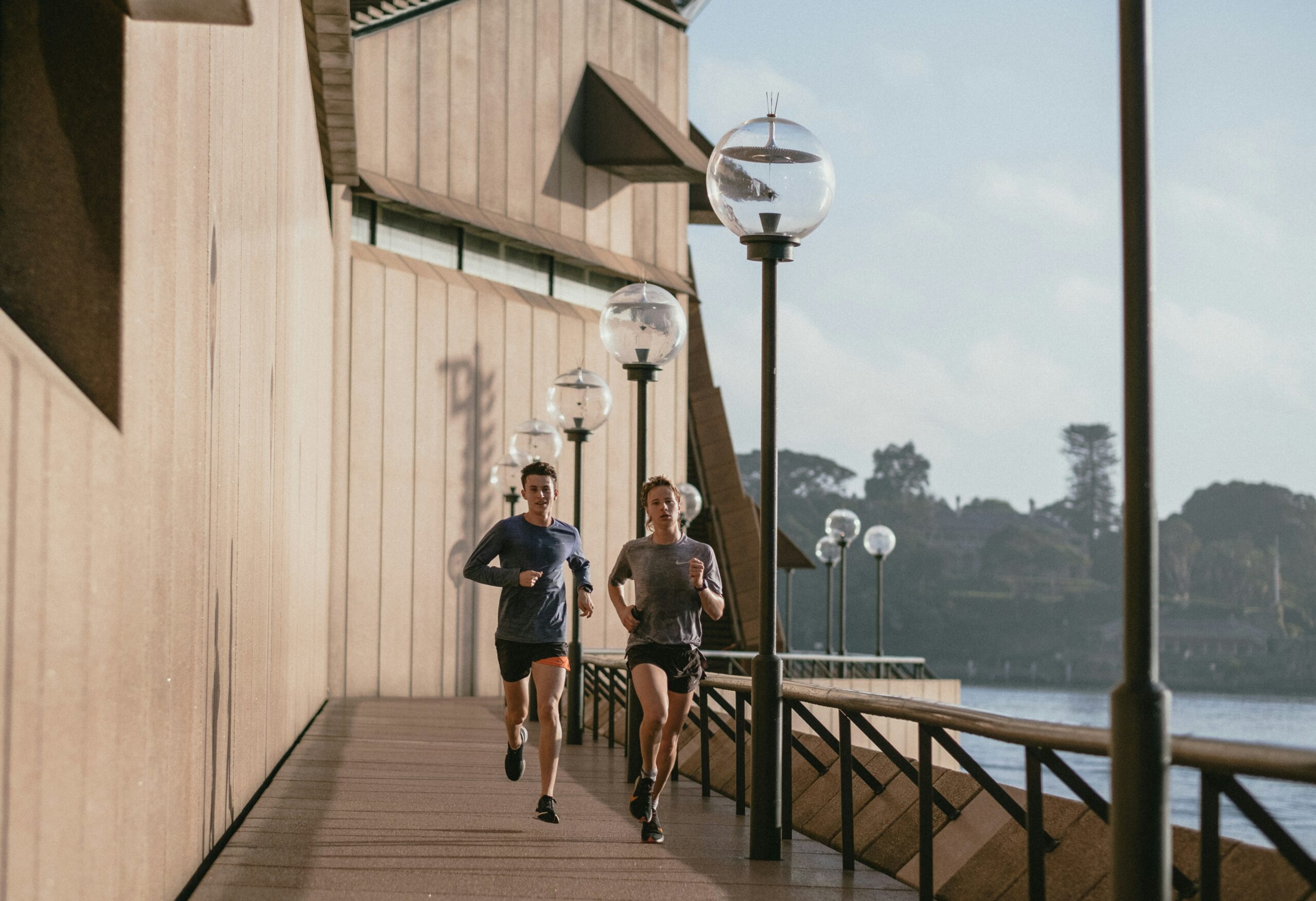 Twee personen lopen samen langs een promenade aan het water tijdens een hardlooptraining